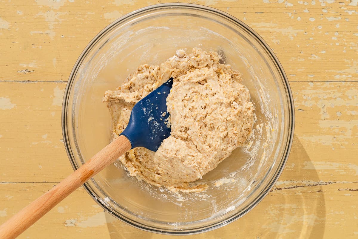 The dough for the shortcakes in a mixing bowl with a rubber spatula.
