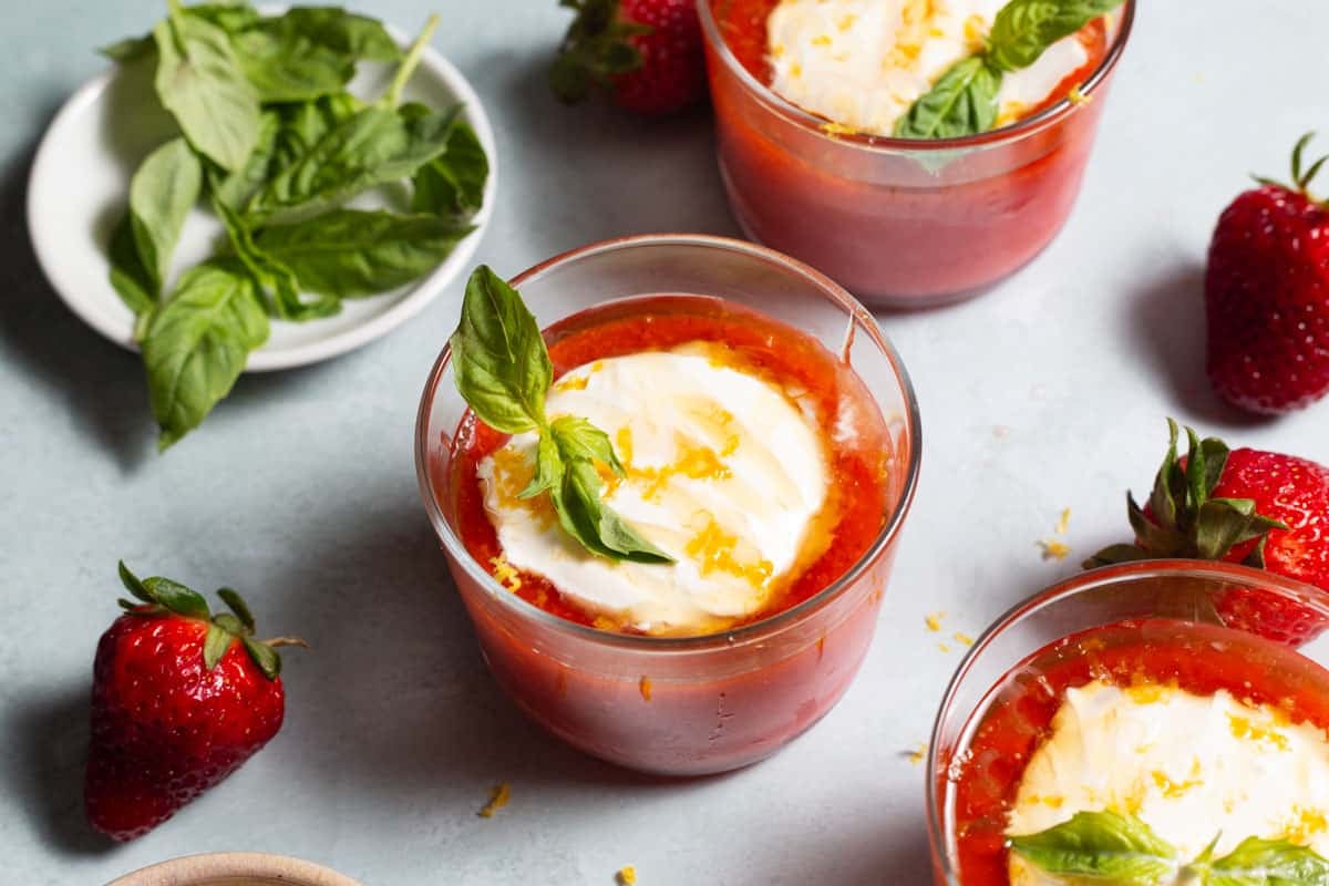 three glasses of strawberry pudding with Crème fraîche, lemon zest, and a sprig of basil.