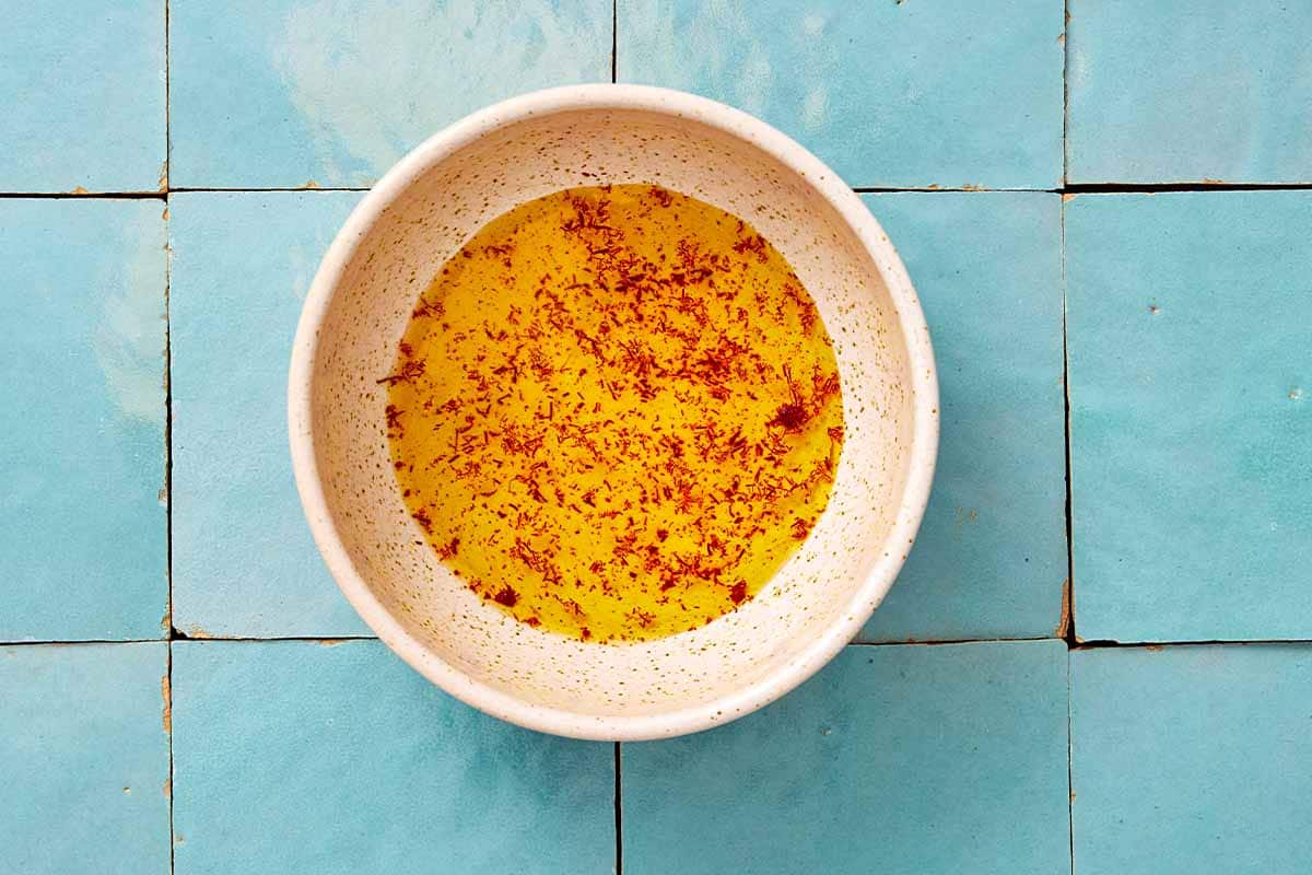 An overhead photo of saffron being bloomed in a bowl.