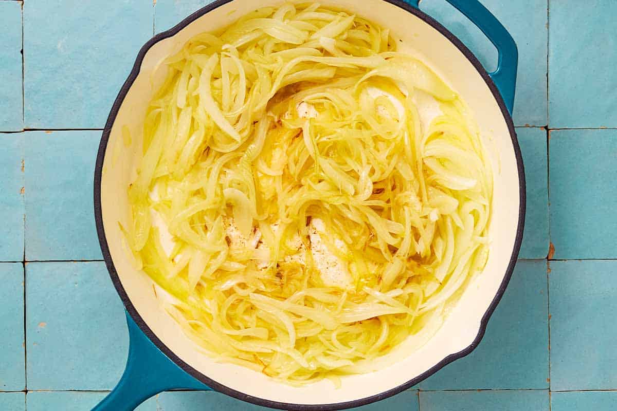 Sliced onion being cooked in a skillet.