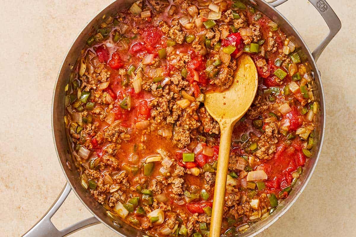 The meat sauce for the Egyptian moussaka being simmered in a skillet with a wooden spoon.