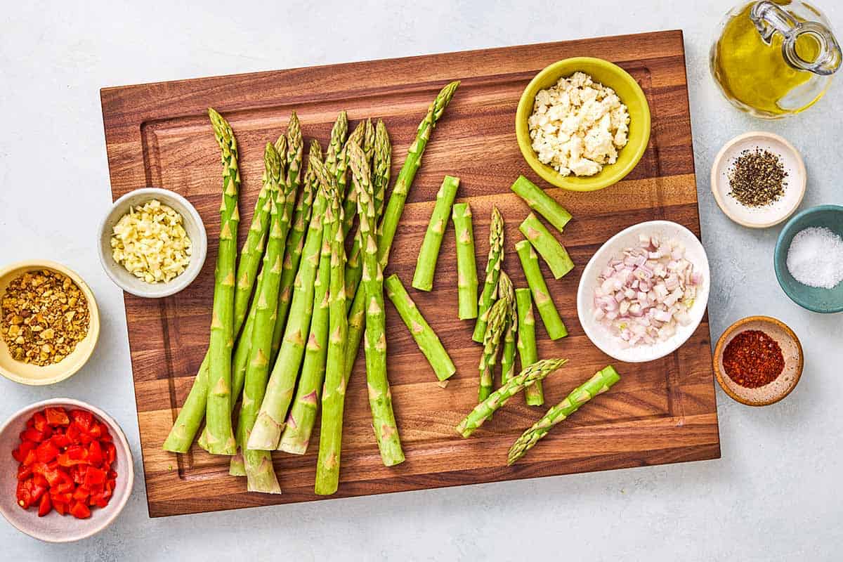Ingredients for sauteed asparagus including asparagus, olive oil, salt, pepper, garlic, shallots, aleppo pepper, za'atar, and feta cheese.
