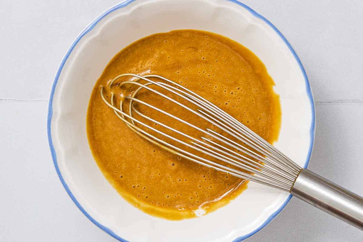 The dressing for the herby freekeh salad in a bowl with a whisk.