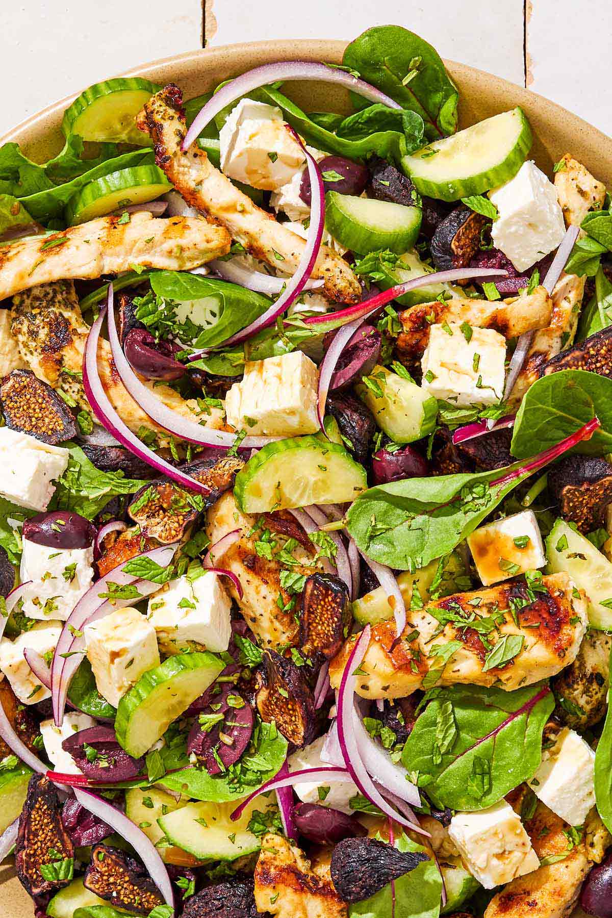 A close up of Greek-stye chicken spinach salad in a serving bowl.