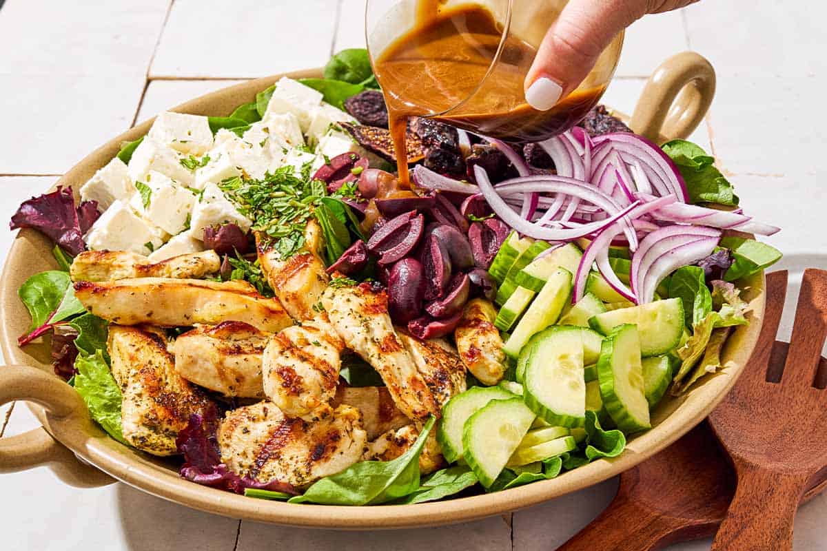 The dressing being poured on the salad, just before being mixed together.