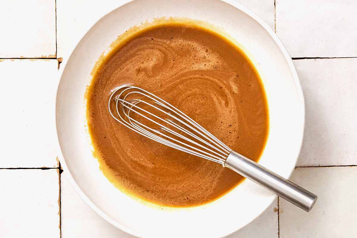 The dressing for the salad in a bowl with a whisk.