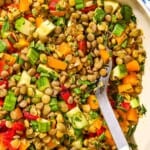 A close up of lentil salad in a serving bowl with a spoon.