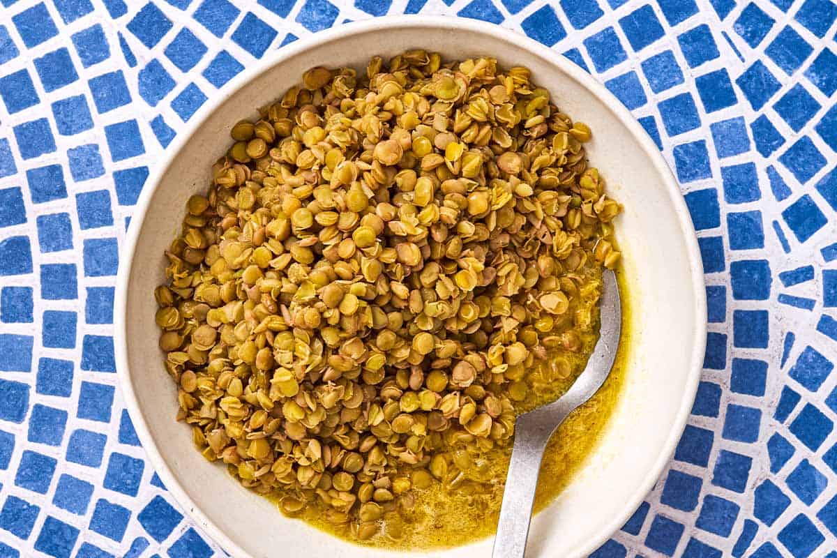 Cooked green lentils in a bowl with a spoon.