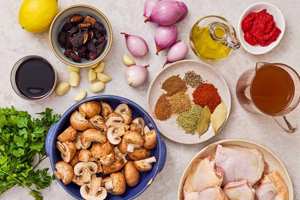 Ingredients for wine braised chicken thighs including chicken thighs, red wine, olive oil, shallots, garlic, tomato paste, chicken broth, bay leaves, rosemary, figs, mushrooms, lemon, parsley, paprika, coriander, pepper, allspice, nutmeg.