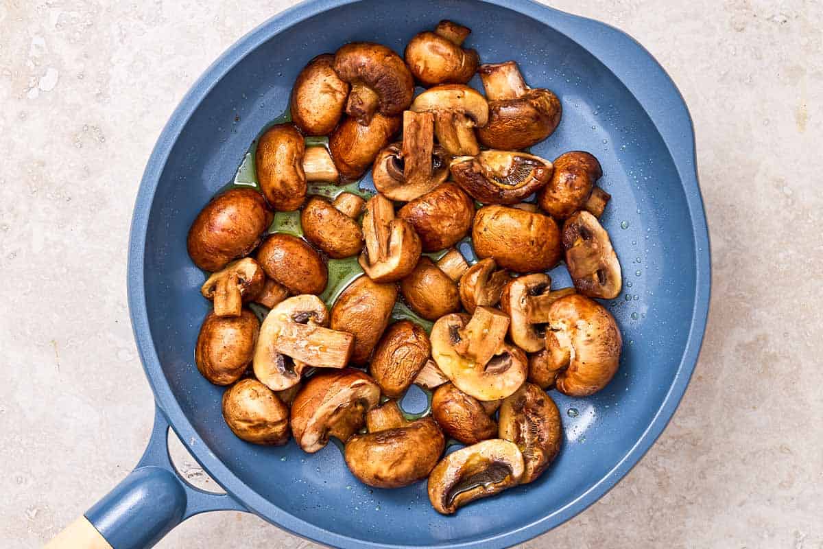 An overhead photo of mushrooms being sauteed in a skillet.