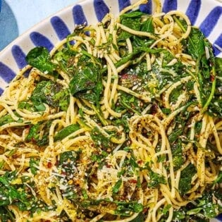 An overhead photo of za'atar garlic spinach pasta on a serving platter with a fork next to a small bowl of za'atar.