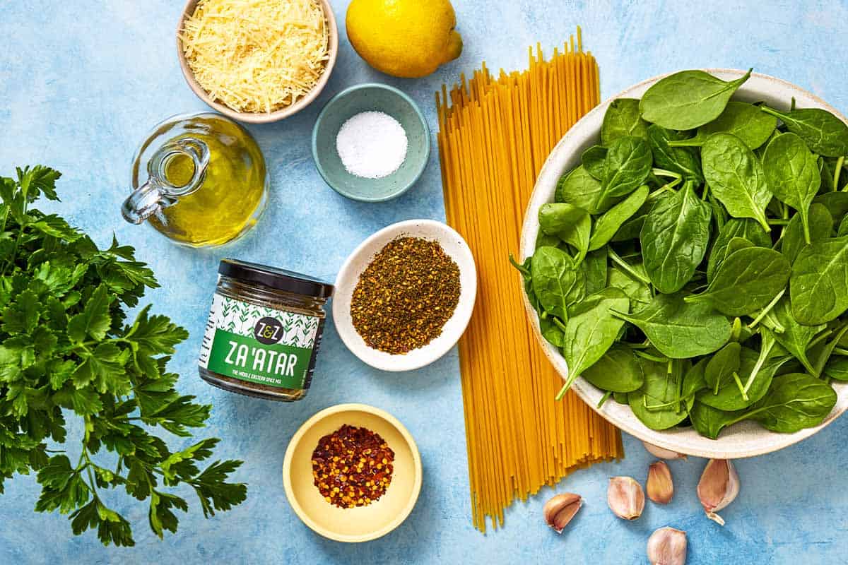 Ingredients for Garlic Spinach Pasta including spaghetti, spinach, olive oil, garlic, red pepper flakes, za'atar, salt, parmesan cheese, lemon, and parsley.