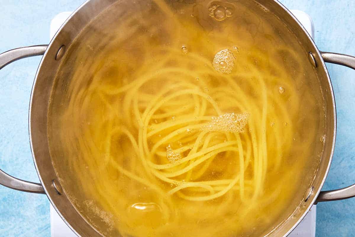 An overhead photo of spaghetti boiling in a pot of water.