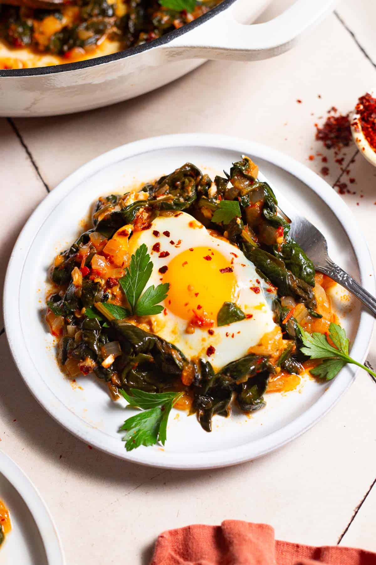 Close up of Overhead a single serving of Turkish spinach and eggs on a white plate.