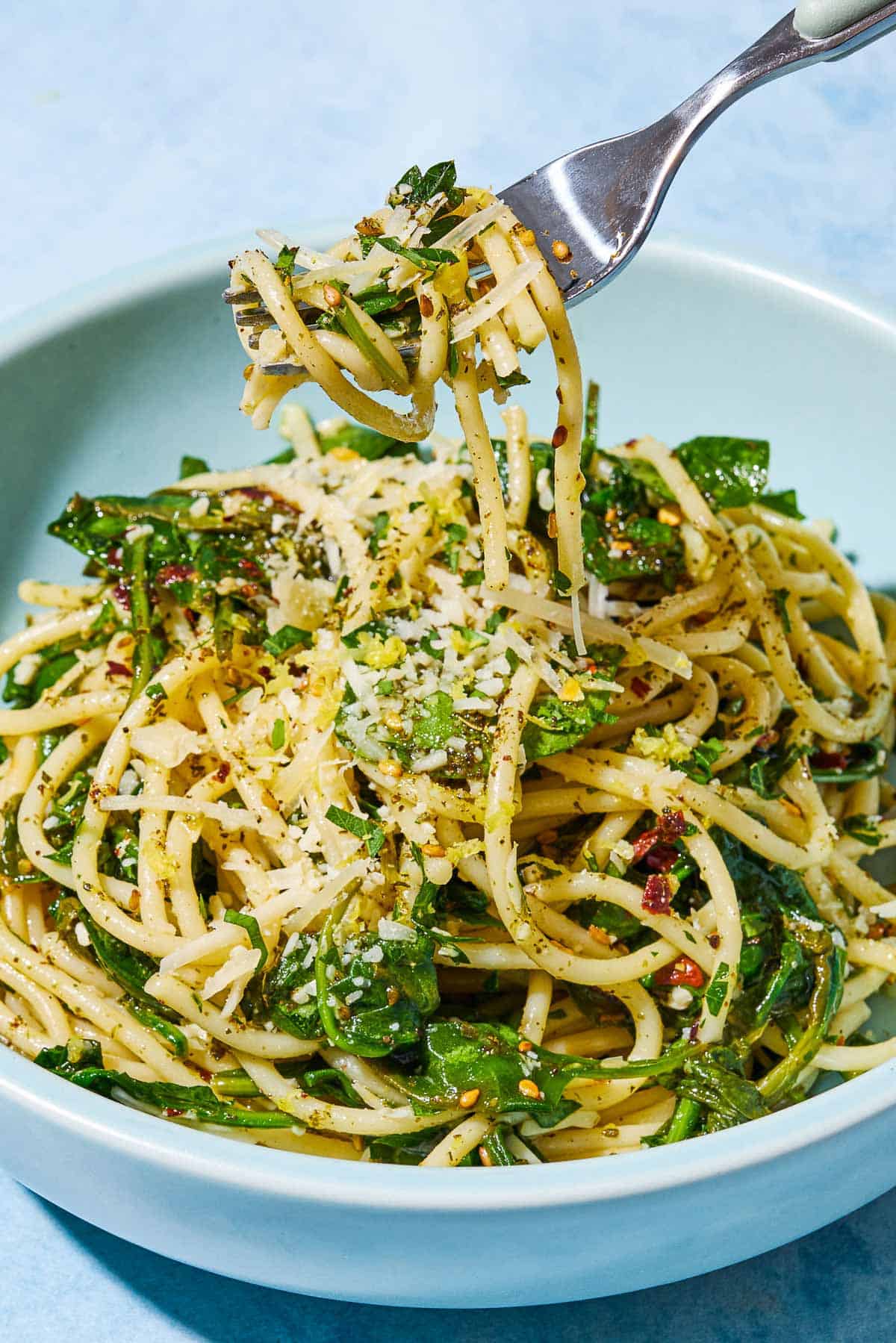 A serving of za'atar garlic spinach pasta in a bowl, with a bite being lifted from it on a fork.