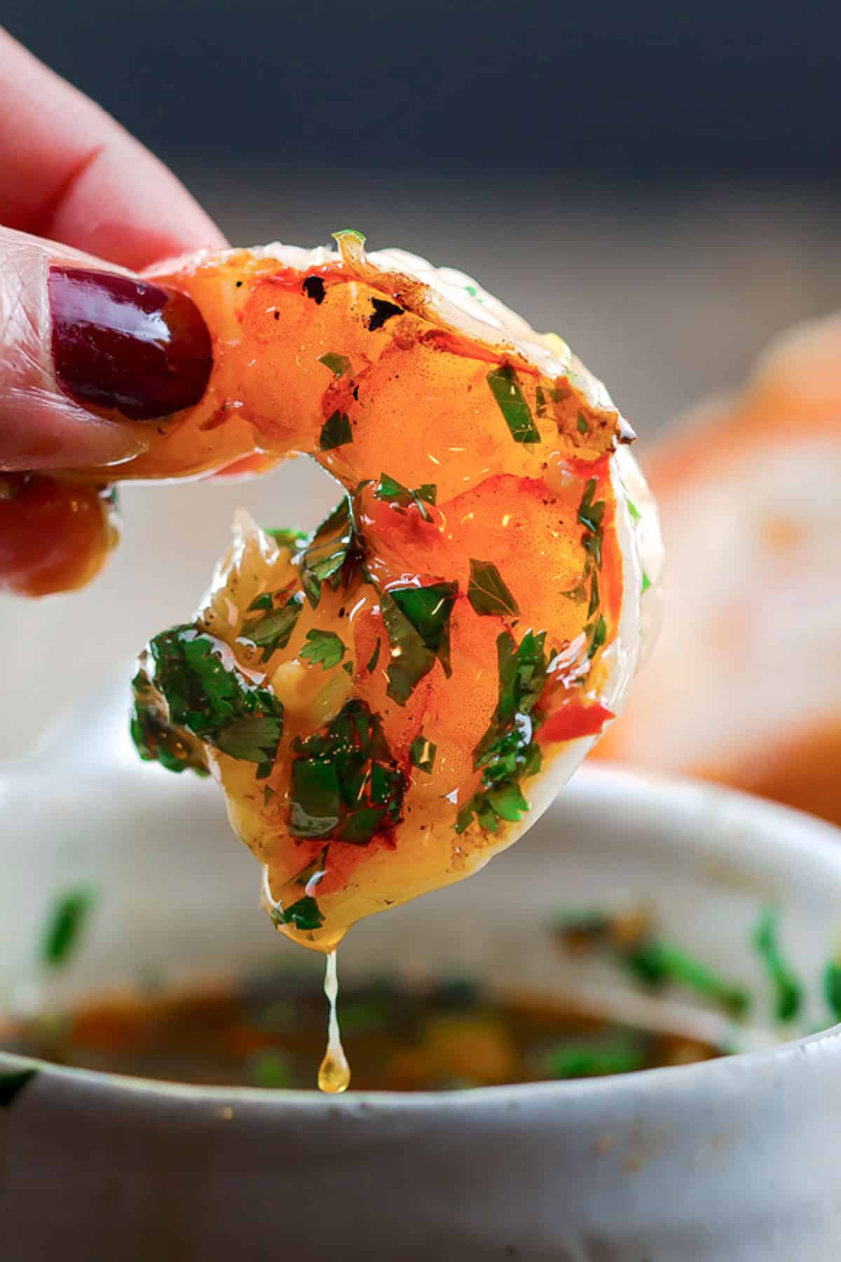 A hand holding a single cilantro lime shrimp.