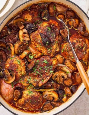 An overhead photo of a pot of wine braised chicken thighs with a serving spoon.