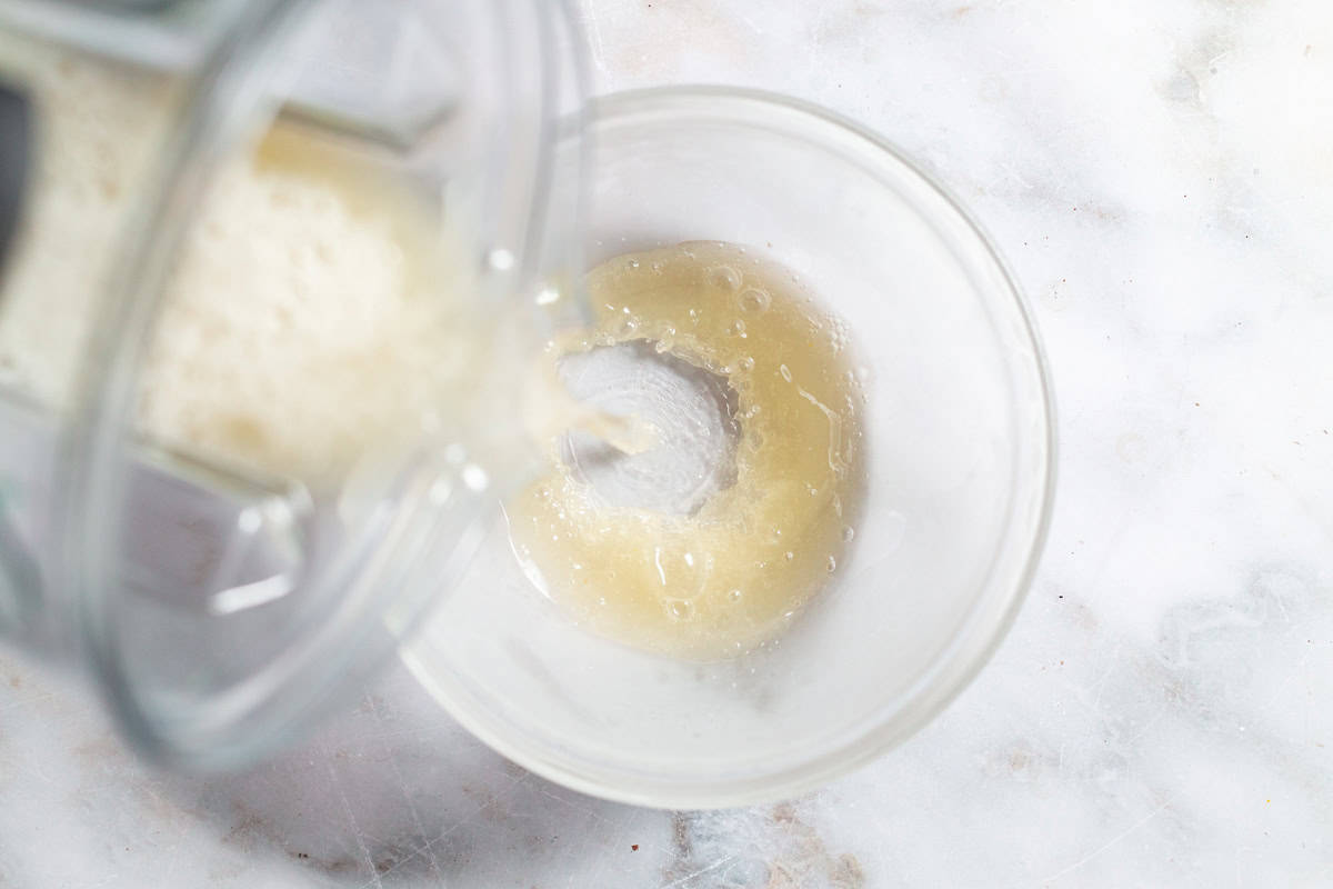 The lemon sorbet mixture being poured from the pitcher of the blender in to a bowl.