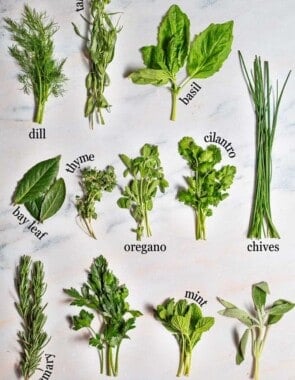 Graphic image labeling 12 fresh herbs against a white marble background: dill, tarragon, basil, bay leaf, thyme, oregano, cilantro, chives, rosemary, parsley, mint, and sage.