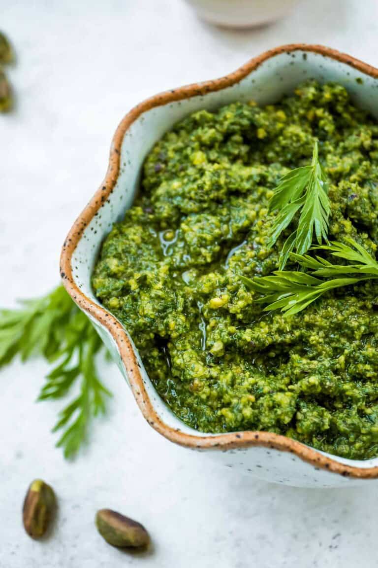 A close up of carrot top pesto in a bowl.