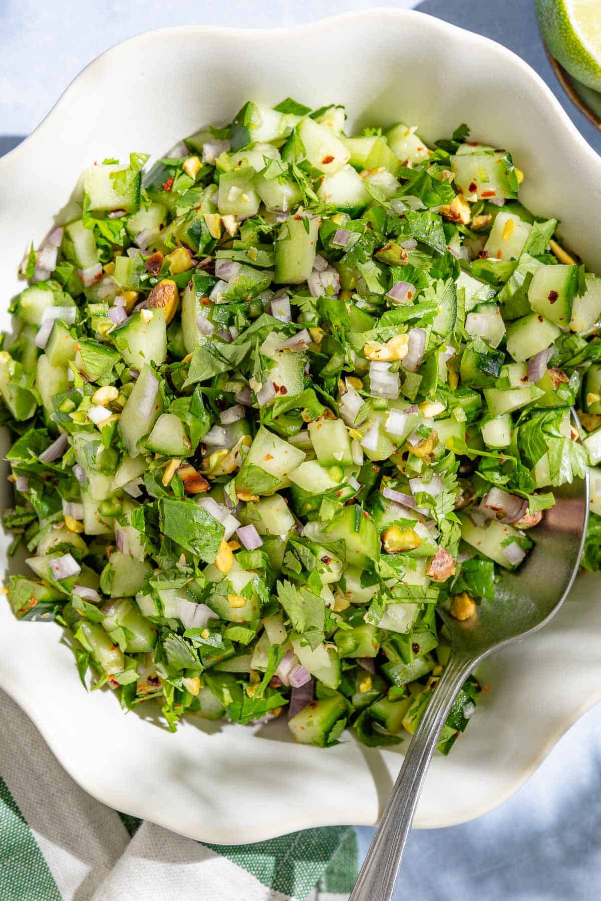An overhead photo of a bowl of cucumber salsa with a spoon.