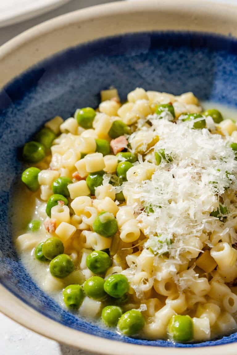 A close up of pasta with peas in a bowl.