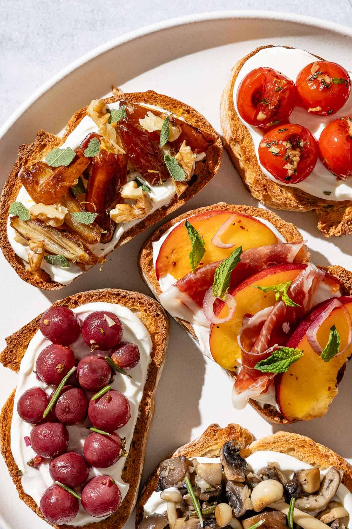 An overhead close up photo of an assortment of the ricotta toasts on a serving plate.