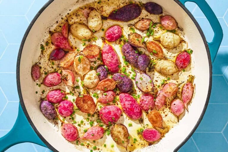 An overhead close up photo of roasted radishes in a skillet garnished with chives.
