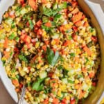 An overhead photo of grilled corn salad in a serving bowl with a spoon. - 19