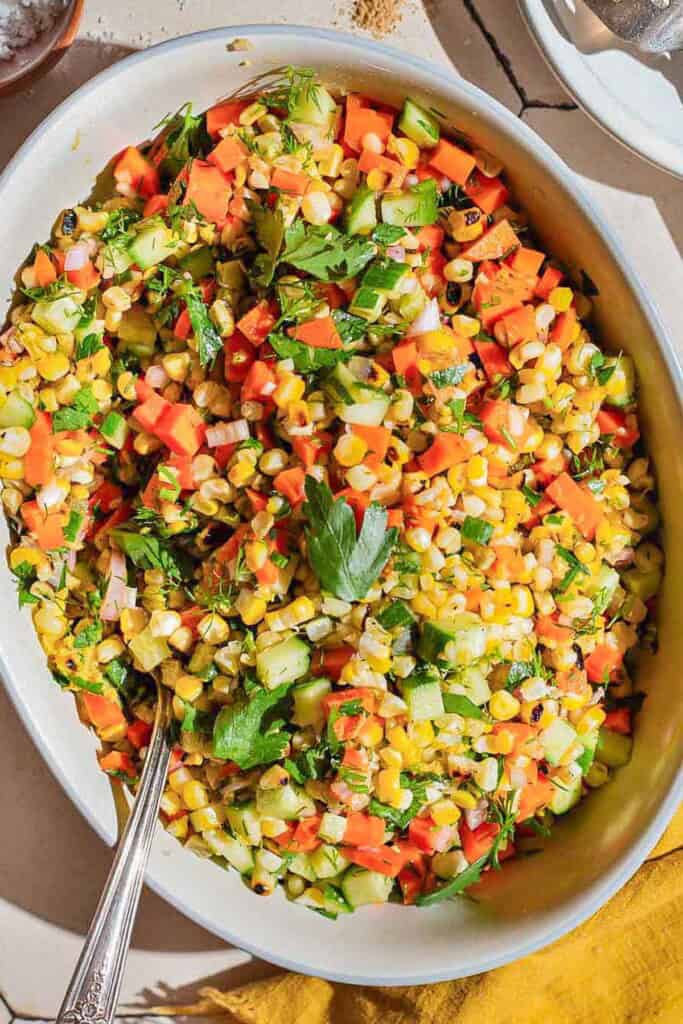 An overhead photo of grilled corn salad in a serving bowl with a spoon.