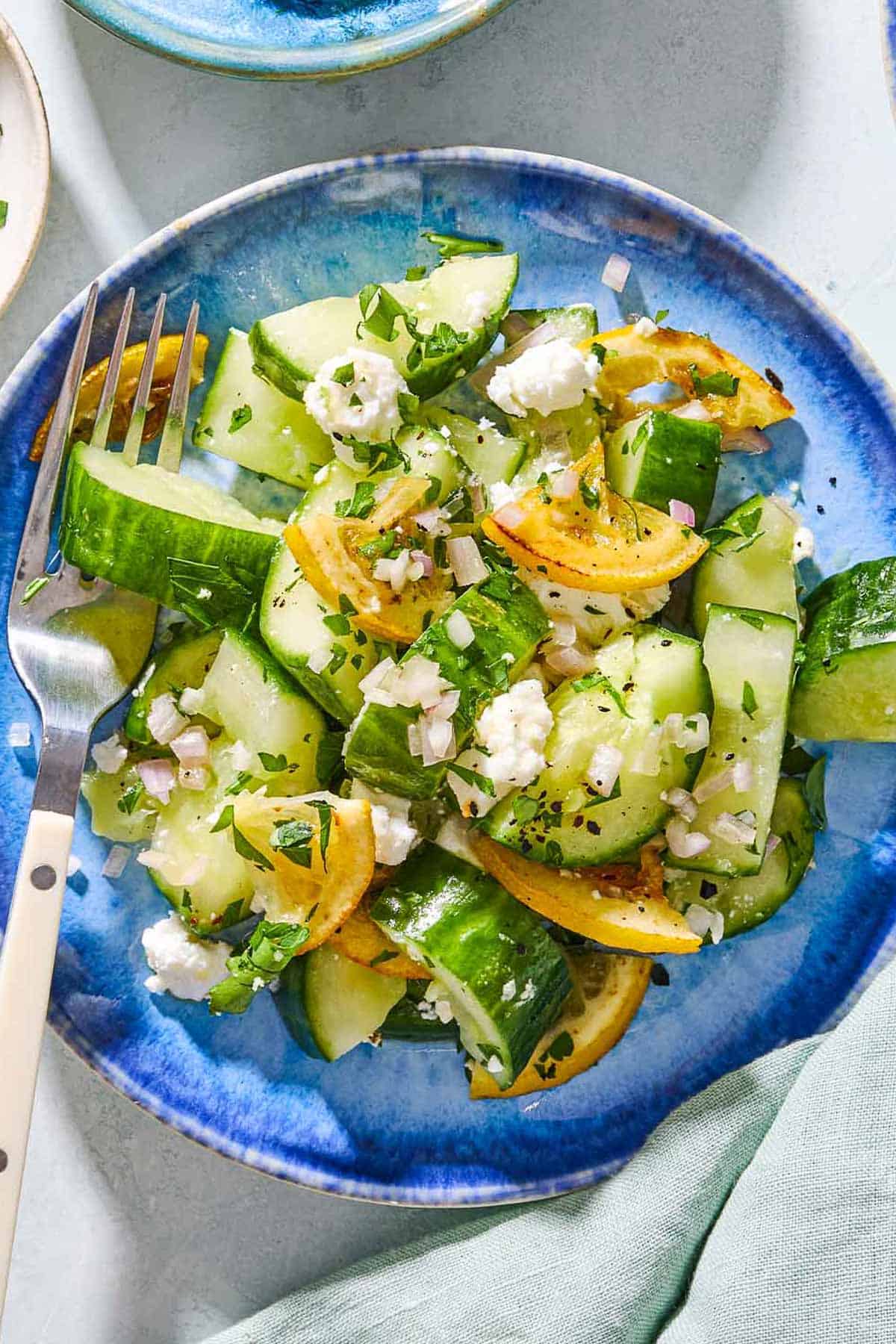 An overhead photo of smashed cucumber salad on a plate with a fork.