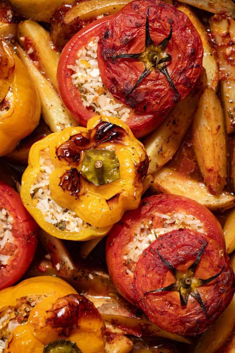 A close up of gemista greek stuffed vegetables with potato wedges.