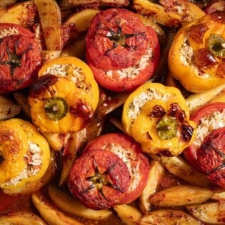A close up of gemista greek stuffed vegetables with potato wedges.