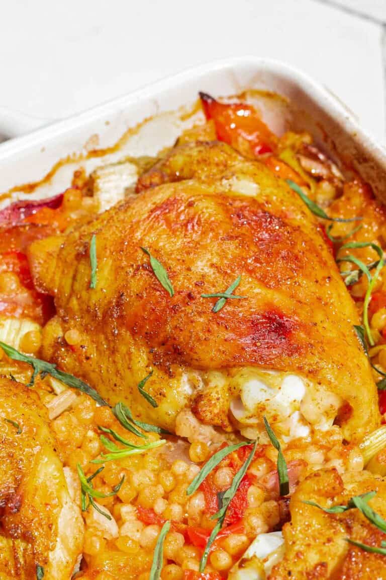 A close up photo of the one pan tomato chicken with baharat, tarragon, and couscous in a baking dish.