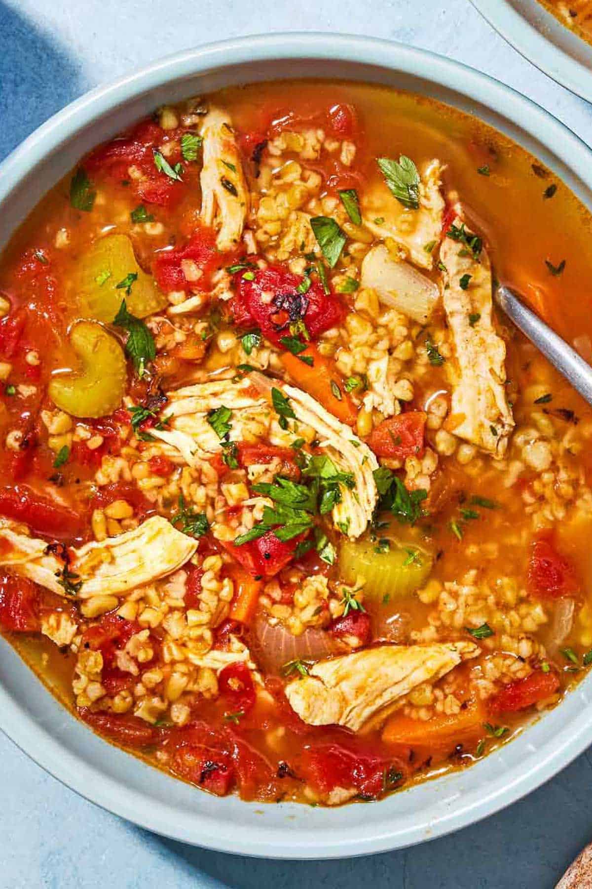 An overhead photo of freekeh soup with chicken in a bowl with a spoon.