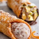 A close up of a filled cannoli with another in the background.