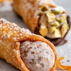 A close up of a filled cannoli with another in the background.