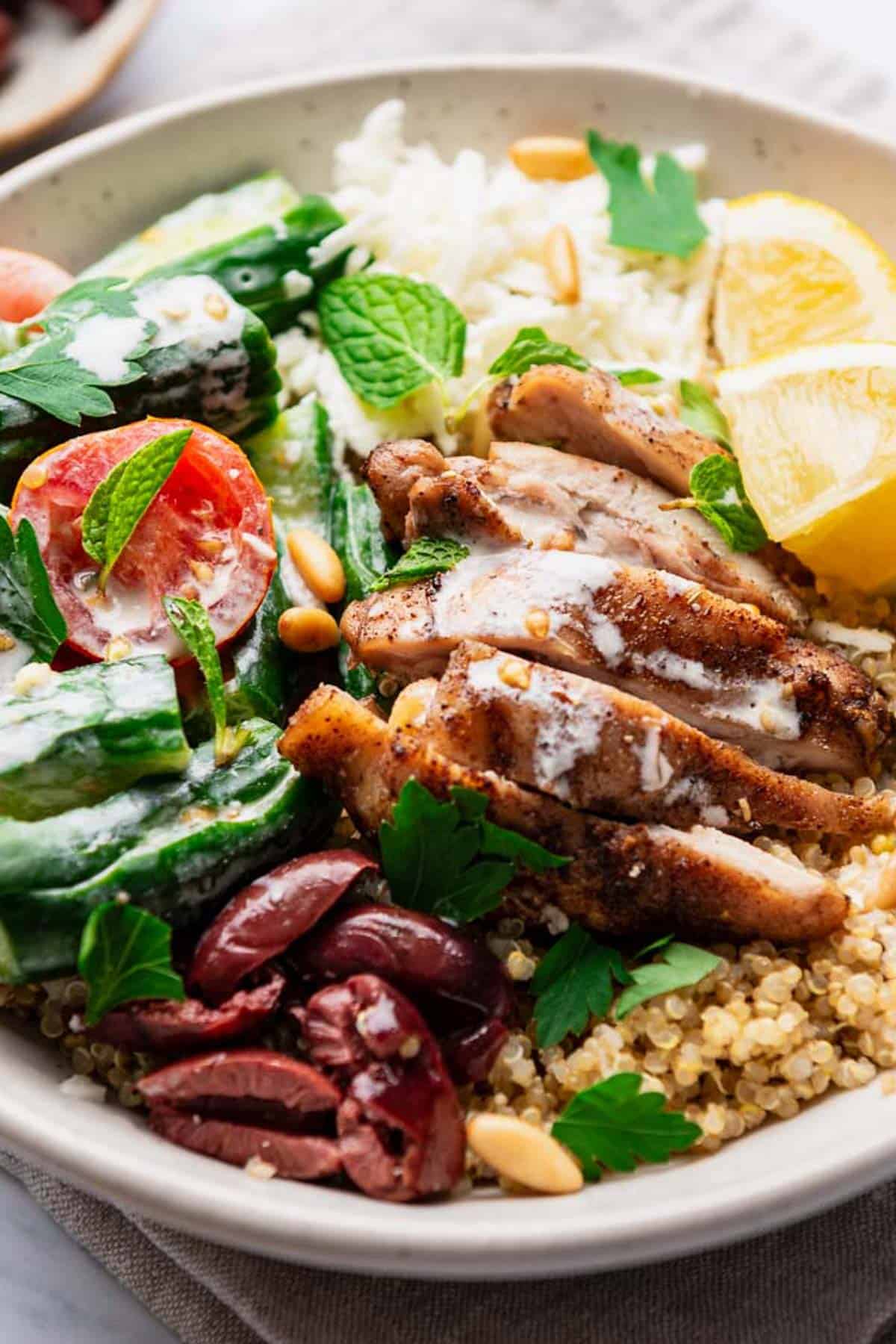 A chicken quinoa bowl topped with chopped parsley and mint.
