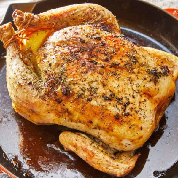 A roasted whole chicken rubbed in italian seasoning in a skillet.