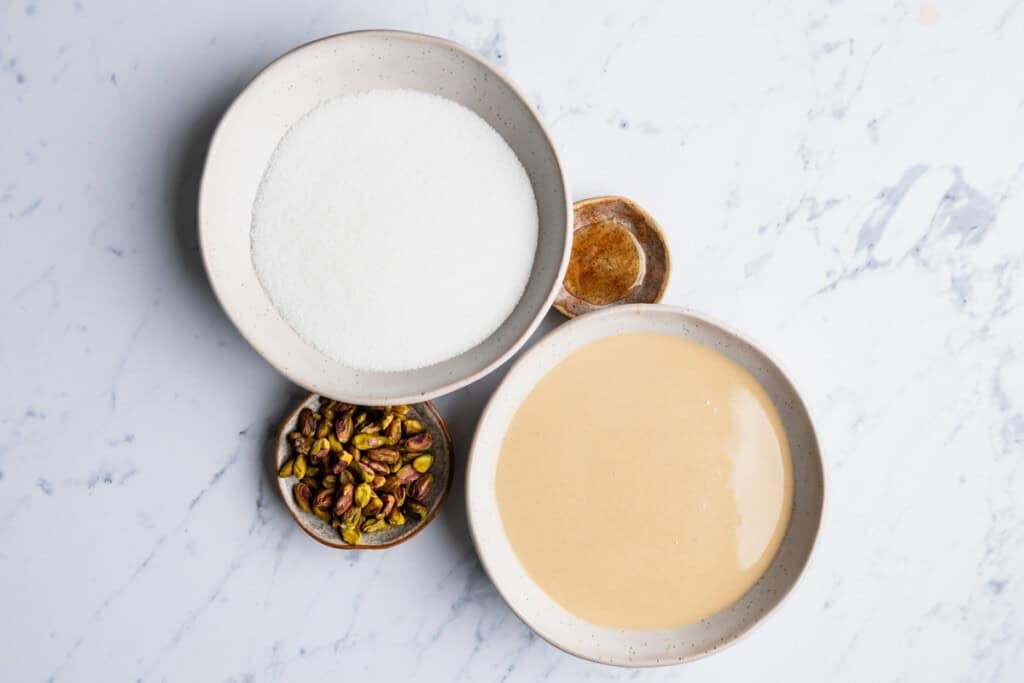 Some of the ingredients for halva including tahini vanilla extract, sugar, and pistachios.