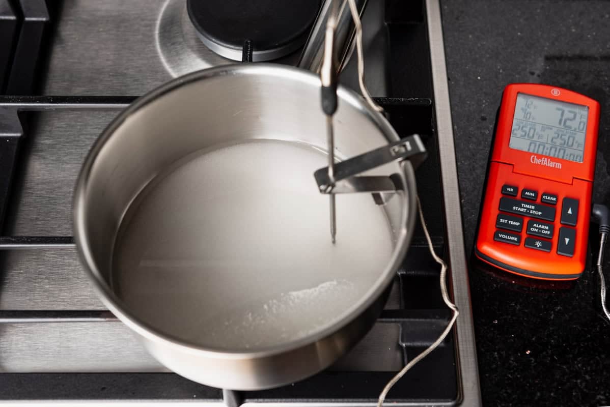 A pot of the sugar and water mixture connected to a candy thermometer.