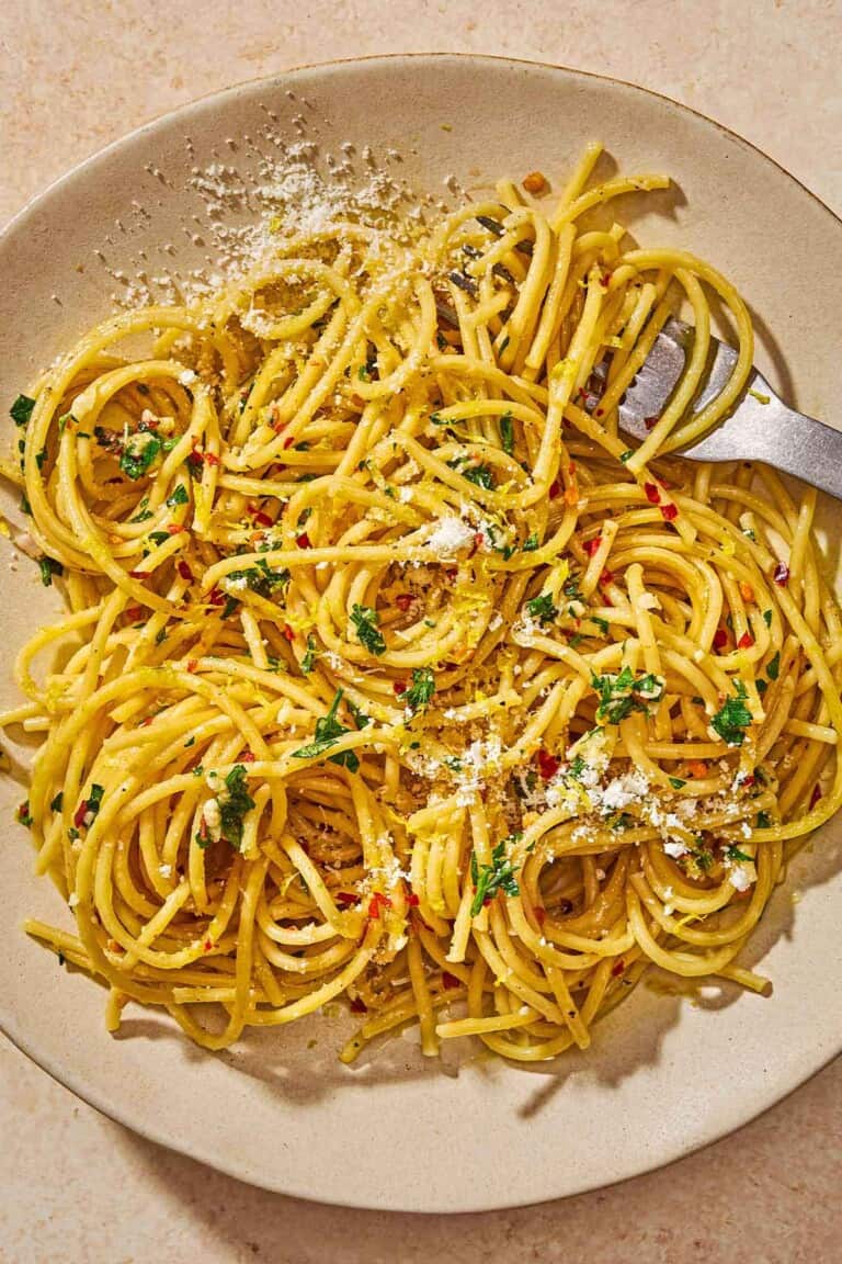 Lemon pasta topped with parsley, lemon zest, red pepper flakes and parmesan on a plate with a fork.