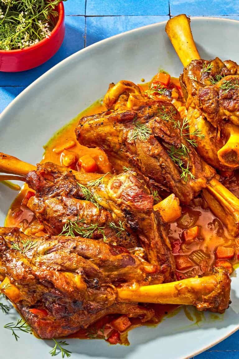 Persian braised lamb on a platter next to a bowl of dill.