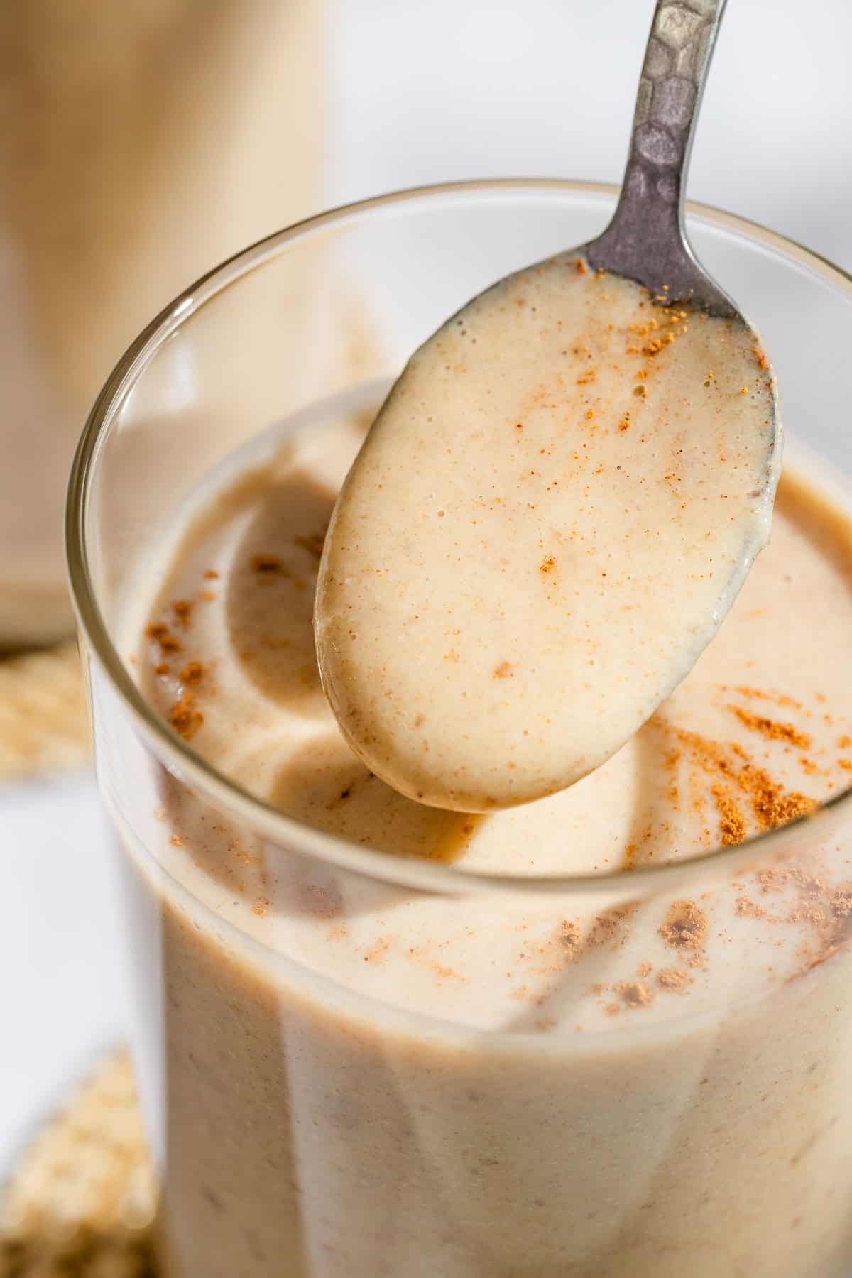 A spoonful of the date shake being held above a glass with the rest of the shake.