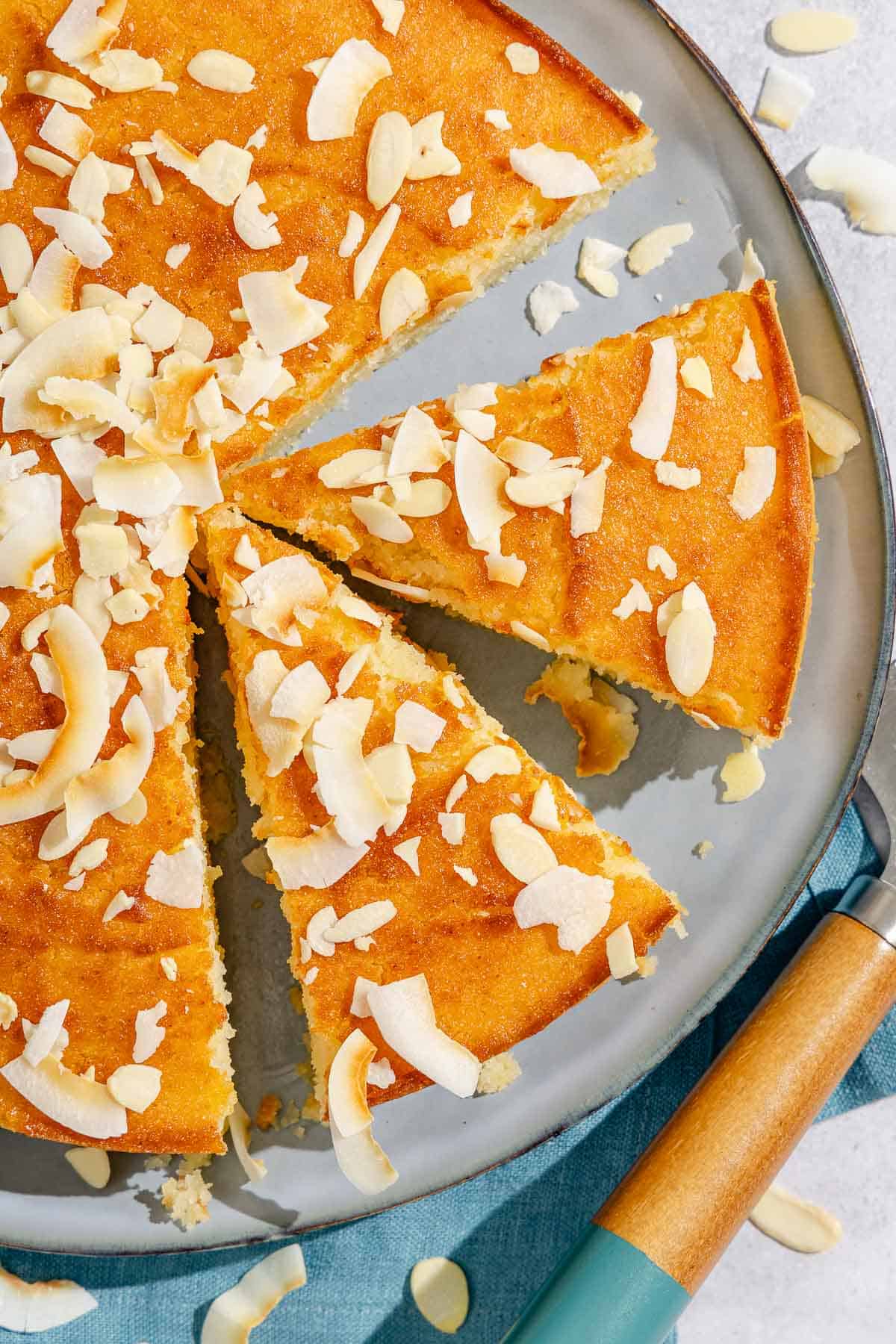 Two slices of the basbousa on a platter with the rest of the cake.