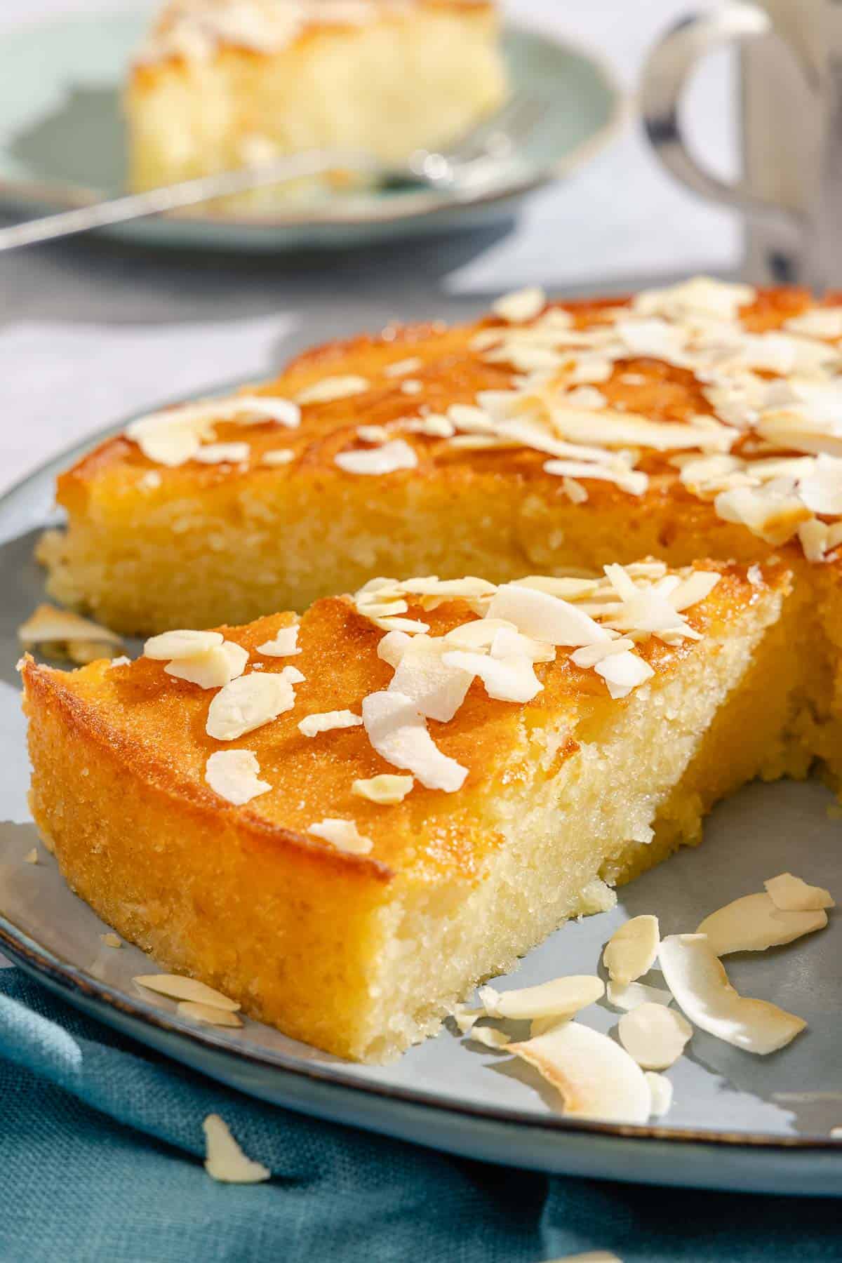 A close up of a slice of the basbousa on the platter with the rest of the cake.