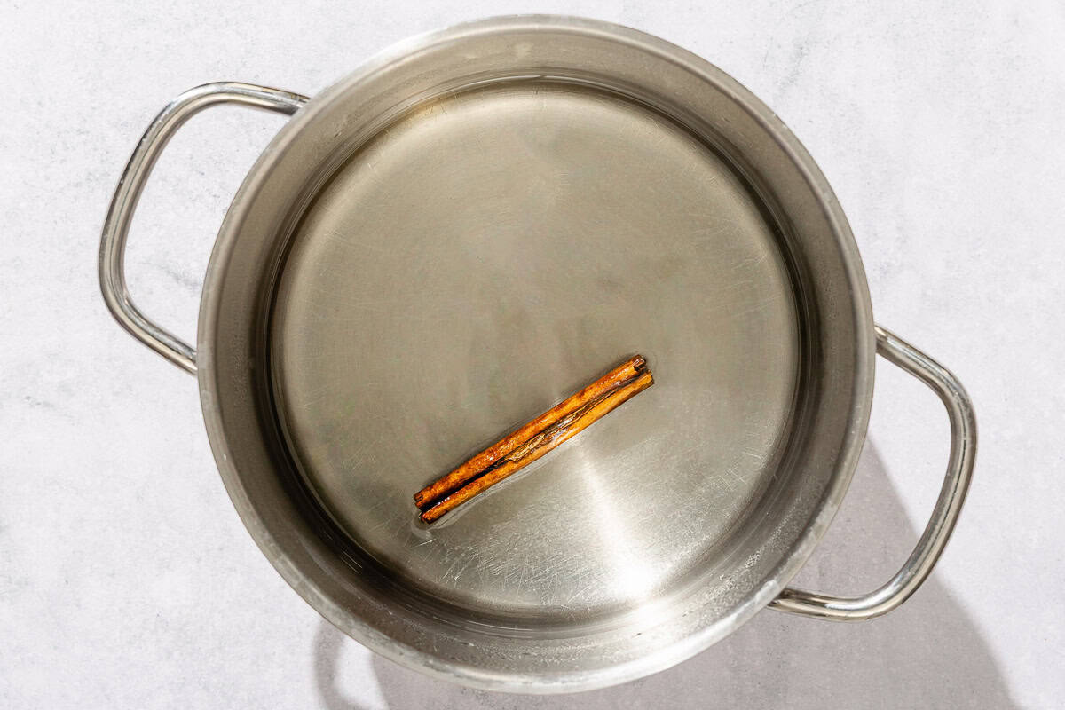Simple syrup with a cinnamon stick in a saucepan.