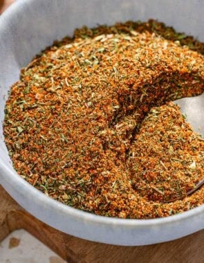 Fish seasoning in a bowl with a spoon on a wooden tray.