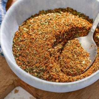 Fish seasoning in a bowl with a spoon on a wooden tray.