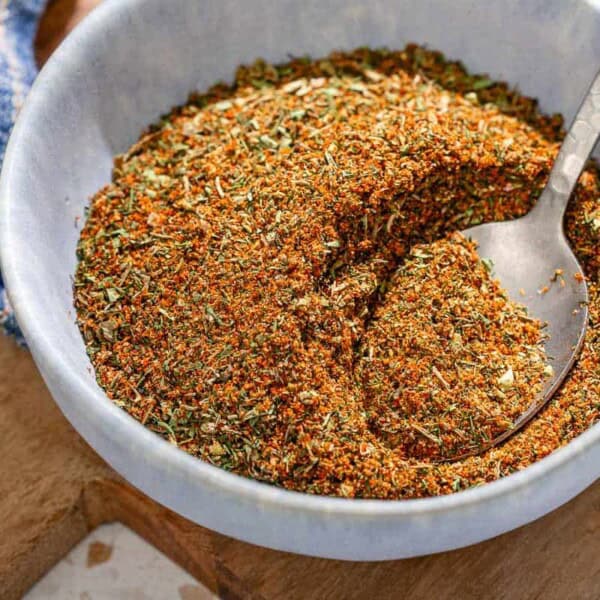 Fish seasoning in a bowl with a spoon on a wooden tray.
